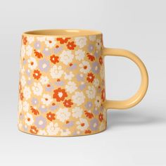 a yellow and blue flowered coffee mug on a white background with an orange handle