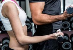 a man and woman holding dumbs in a gym