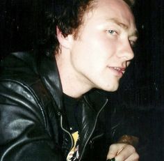 a man in a black leather jacket holding a cell phone