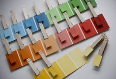 several pieces of colored paper with clothes pins attached to them