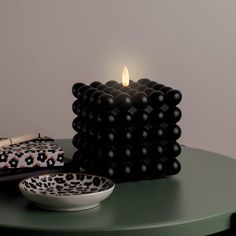 a candle sitting on top of a green table next to a bowl and some candles