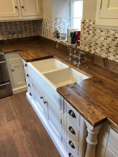 a kitchen with wooden counter tops and white cabinets, an oven and dishwasher