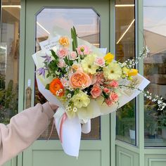 a woman holding a bouquet of flowers in front of a green door