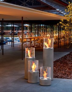 three fire pits sitting next to each other on top of a cement floor covered patio