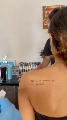 the back of a woman's shoulder with words written on her left arm and in blue gloves