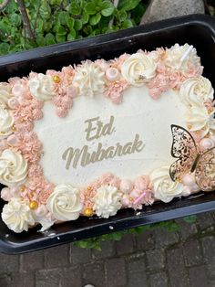 a birthday cake with flowers and butterflies on the top is in a black box that says eid muhare