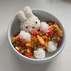 a white bowl filled with rice and veggies next to a small stuffed animal