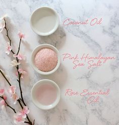 pink himalayan salt and rose essential oil in small white bowls on a marble countertop