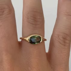 a woman's hand with a gold ring and a green gemstone on it