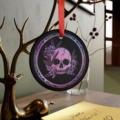 an ornament with a skull and flowers on it sitting next to a tree