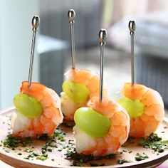 four shrimp skewers on a plate with green garnish