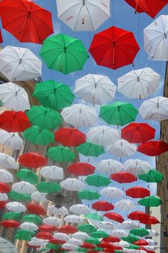 many different colored umbrellas hanging in the air