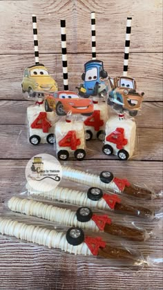 cars and trucks cupcakes in plastic wrappers on a wooden table with black and white striped straws