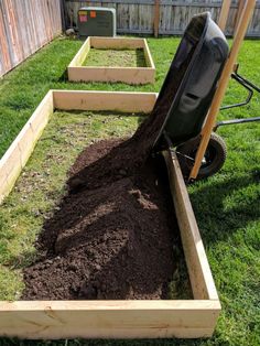 a wheelbarrow filled with dirt next to a pile of soil in a yard