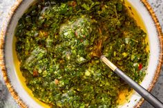 a white bowl filled with green food and a spoon