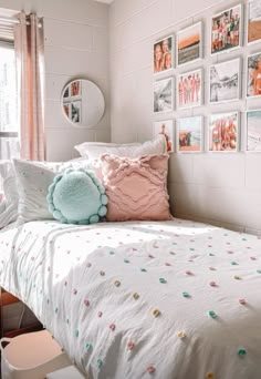 a white bed topped with lots of pillows next to a wall covered in pictures and photos