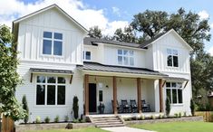 a white two story house with black shutters on the front and side doors, windows, and steps leading up to it