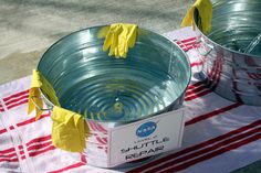 two buckets with yellow flowers in them sitting on a red and white table cloth