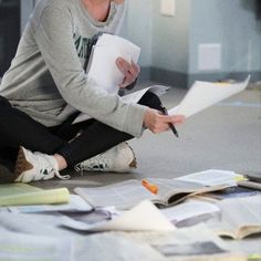 a woman is sitting on the floor with papers