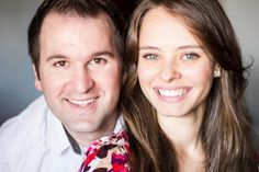 a man and woman posing for a photo with their heads turned to the side, smiling