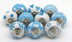 a bunch of blue and white ceramic knobs with flowers on the front, one has a silver plated center