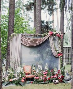 a chair sitting in the middle of a forest filled with flowers and greenery next to a painting