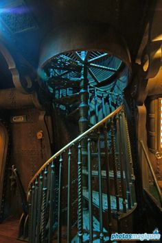 a spiral staircase in the middle of a building with blue lights on each side and metal railings