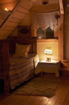 a bed sitting under a window next to a night stand with a lamp on it