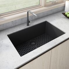 a kitchen sink sitting next to a window with fruit on the counter top in front of it