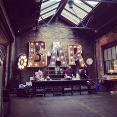 a man standing in front of a sign that says bar with lights on the side