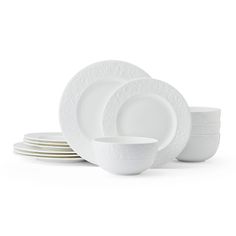 the white dinnerware is stacked on top of each other and has an intricate design