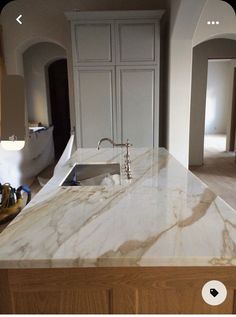 a large kitchen with marble counter tops and white cupboards in the backround