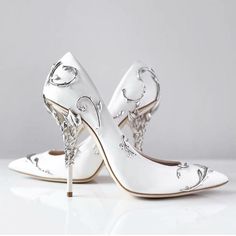 a pair of white high heeled shoes with silver decorations