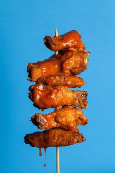 chicken skewers with sauce drizzled on them against a blue background