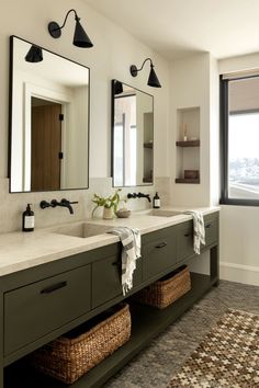 a bathroom with two sinks, mirrors and baskets on the counter top in front of a large window