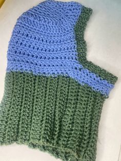 a green and blue knitted hat sitting on top of a table