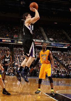 a basketball player is jumping up to dunk the ball in front of his opponent