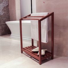 a bathroom with a toilet, tub and towel rack on the floor in front of it