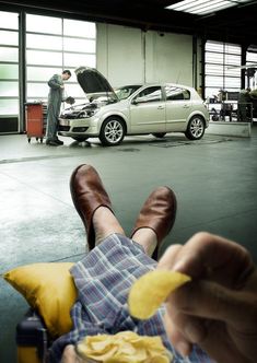 a man sitting in a chair with his feet up next to a car