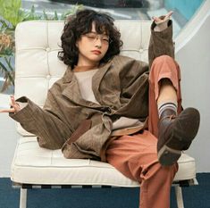 a young man sitting on top of a white chair with his feet up in the air