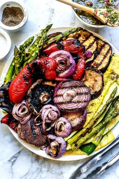 a white plate topped with grilled vegetables on top of a table next to silverware