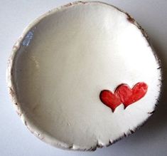 two red hearts are in the middle of a white bowl