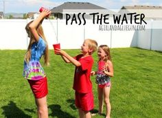 three children are playing in the grass with a red cup and some water hoses