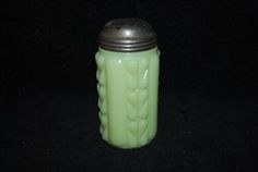 a green glass jar sitting on top of a black table