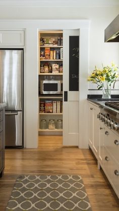 a kitchen with white cabinets and stainless steel appliances in the center, along with an area rug on the floor