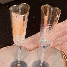 two champagne flutes sitting on top of a table next to a plate with gold rims