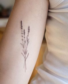 a woman's arm with three lavender flowers on the back of her left arm