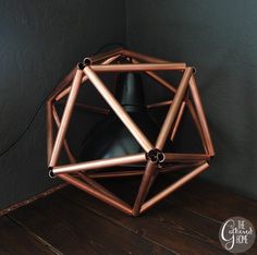 a metal object sitting on top of a wooden floor next to a black light bulb