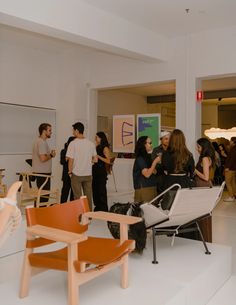 a group of people standing around in a room with chairs and paintings on the walls