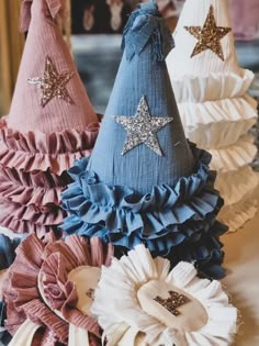 three party hats with ruffles and stars on them, one is blue and the other is pink